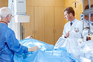 Ärzte im Gespräch mit einer Patientin bei einer Herzkathederuntersuchung 